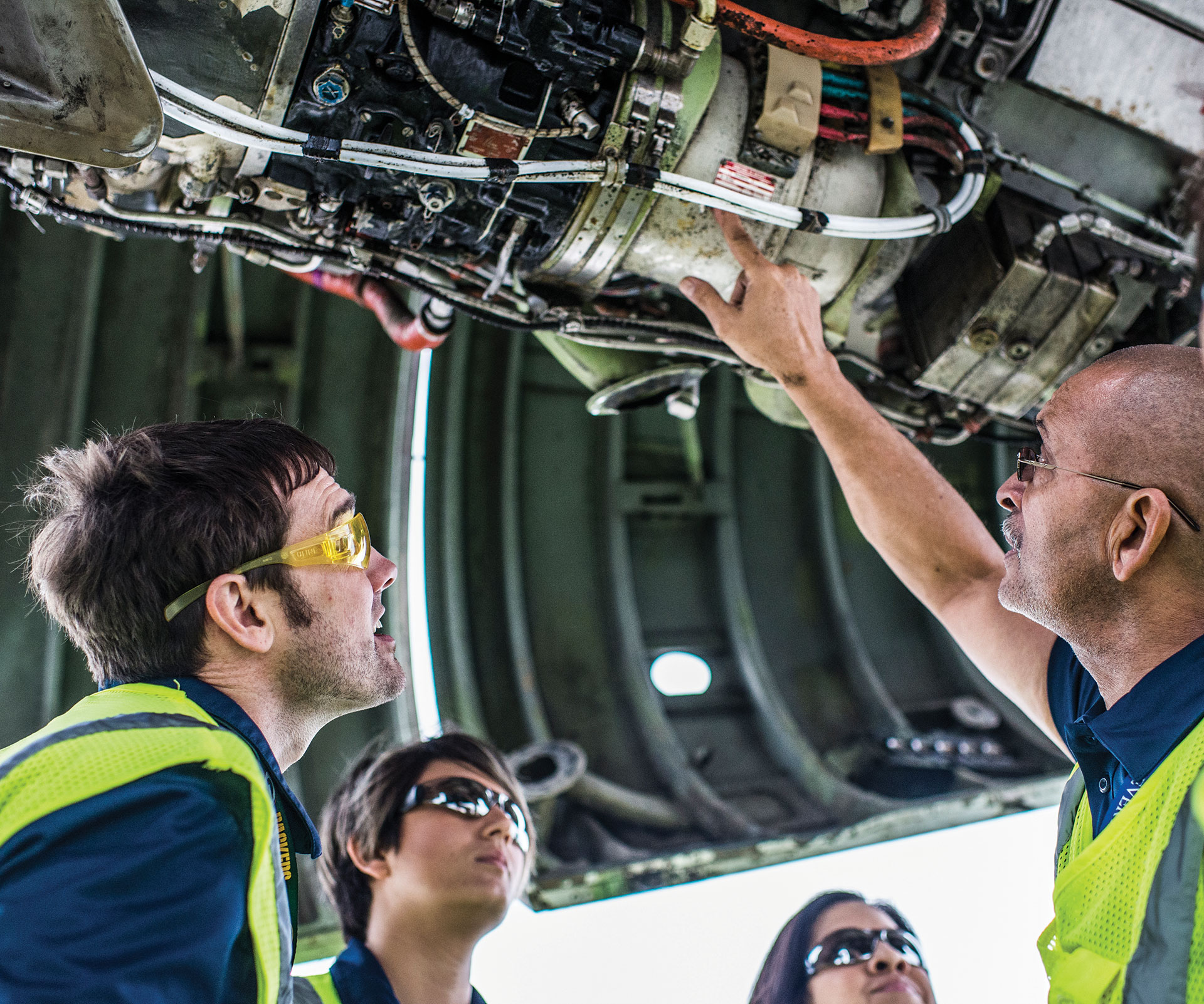Aeronautics students listen to instructor explain parts of an aircraft engine