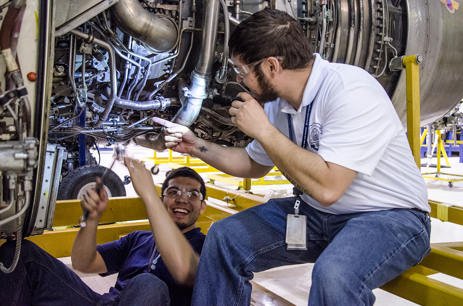 Aeronautics students smiling and working on aircraft engine