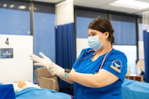 A nursing student puts on gloves before beginning a simulation exercise in the School of Nursing