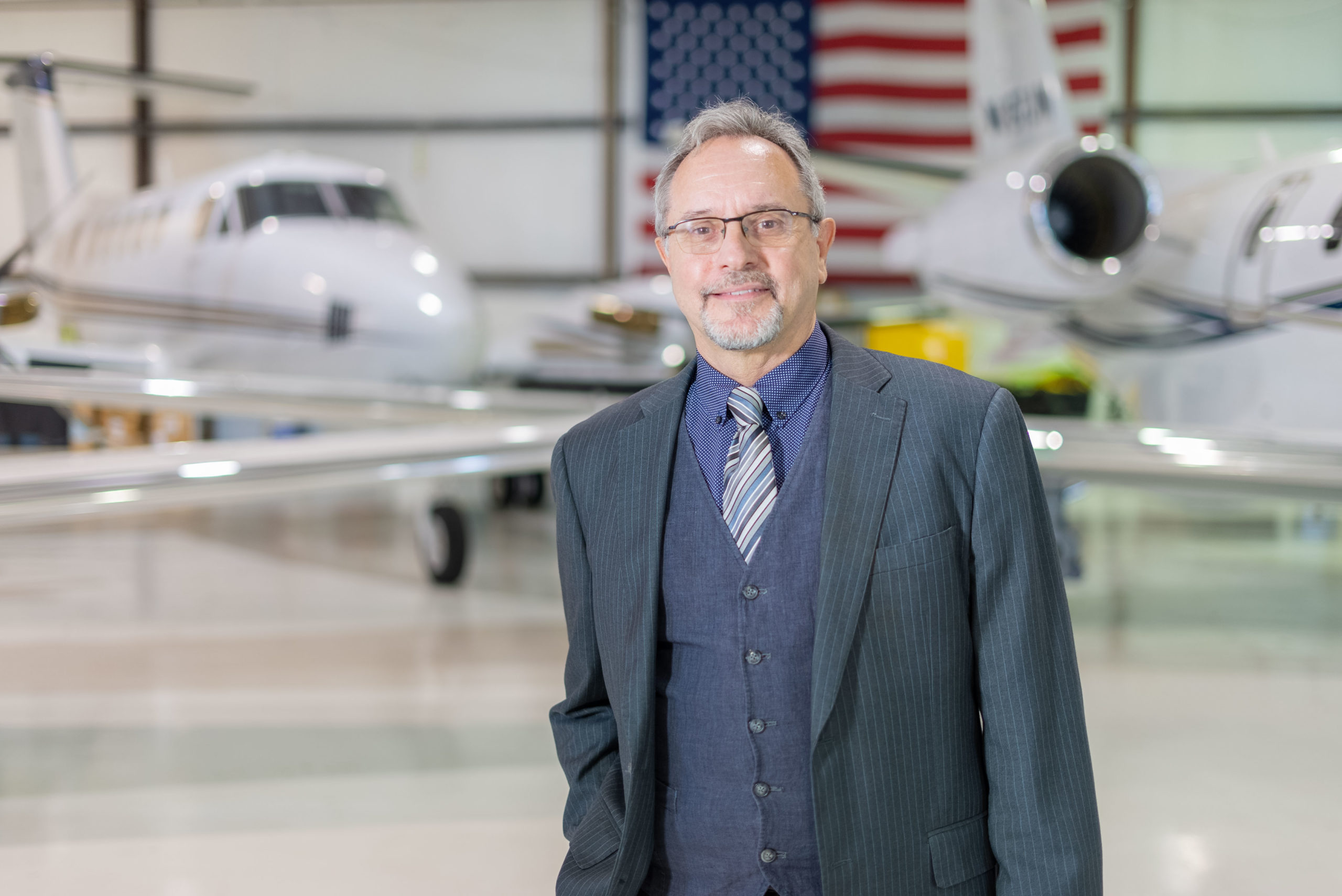Stan Younger stands inside of a hangar at the College of Aeronautics